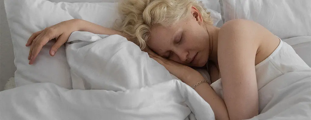 Young woman sleeping in a bed with white bed linen
