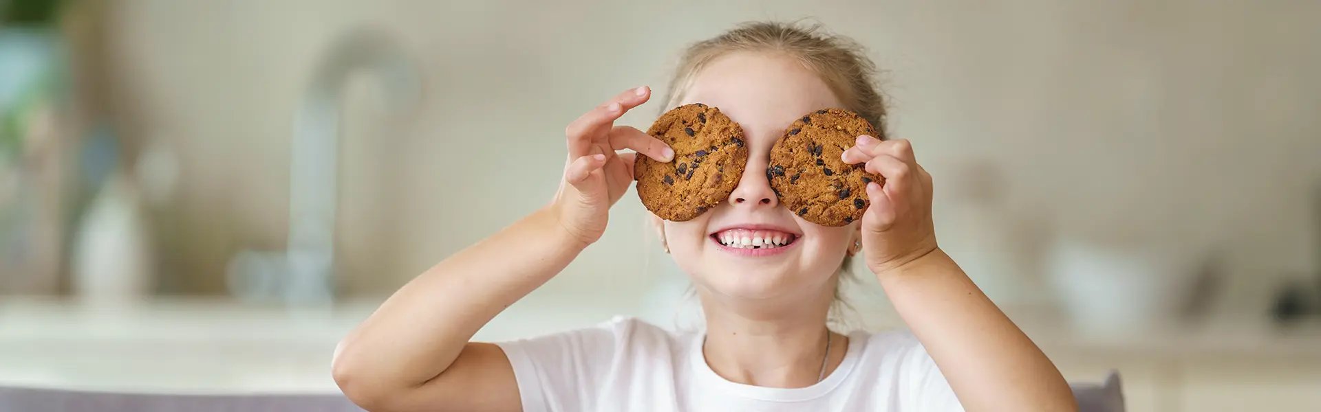 Girl holding two cookies in front of her eyes